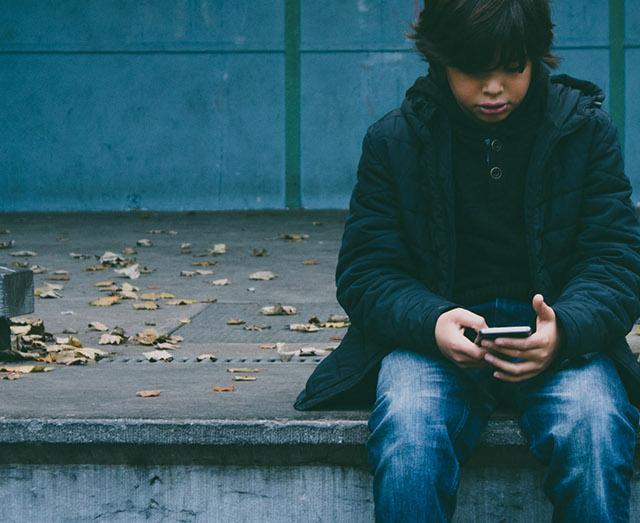 photo of a person sitting on outdoor steps looking at their phone